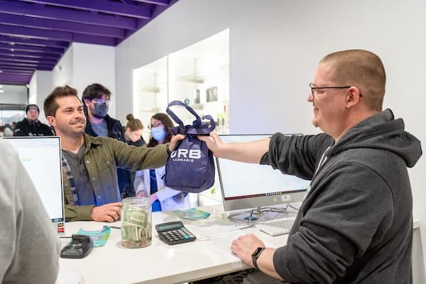 Budtender Giving a URB Cannabis Brand Bag to a Happy Customer Budtender Giving a URB Cannabis Brand Bag to a Happy Customer
